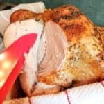 A cooked turkey on a platter with a red knife.