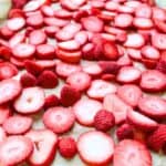 Frozen strawberries on a parchment paper lined baking sheet.