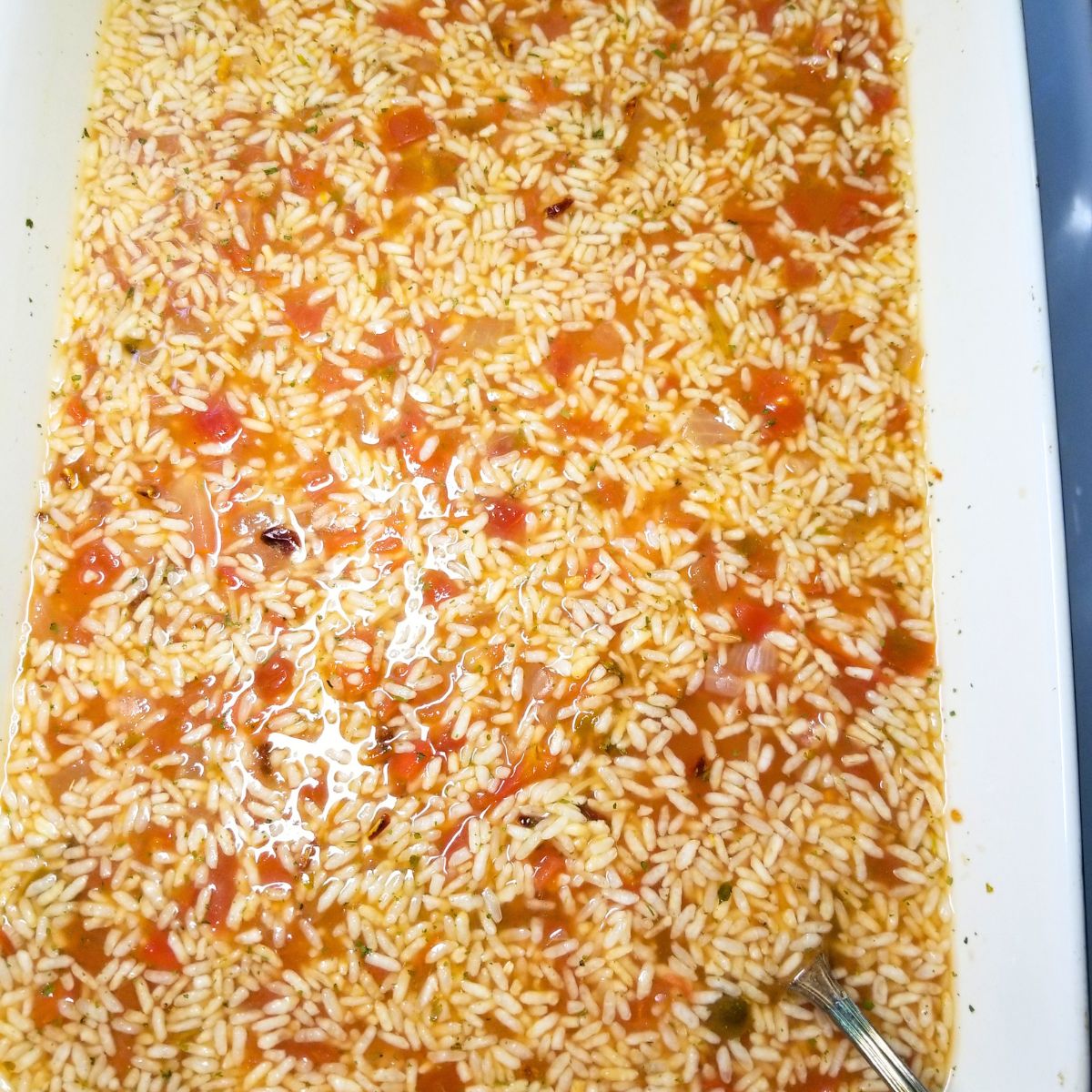 Rice, broth, salsa, and water mixed in a baking dish.