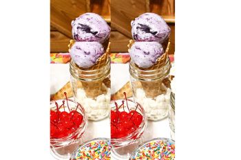 Blueberry No Churn Ice Cream in waffle cones with sprinkles and cherries in the picture.