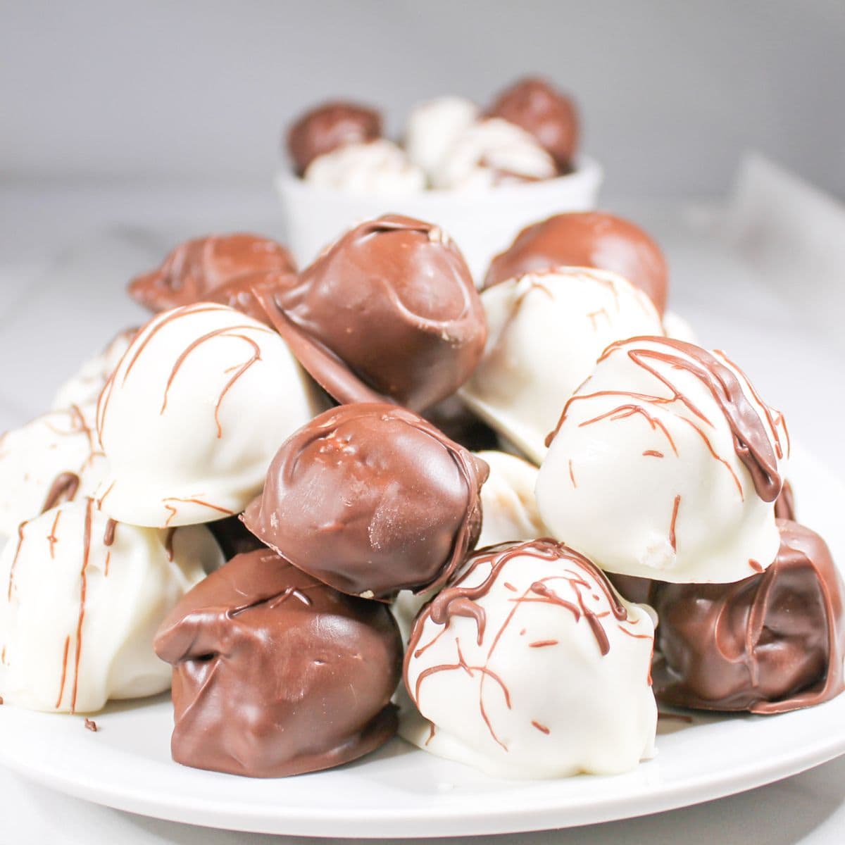 Peanut butter balls stacked on a white dish.