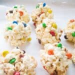 Popcorn balls with M&M's on white parchment paper.