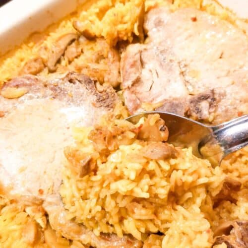 Baked pork chop and rice casserole in a baking dish with a spoon.