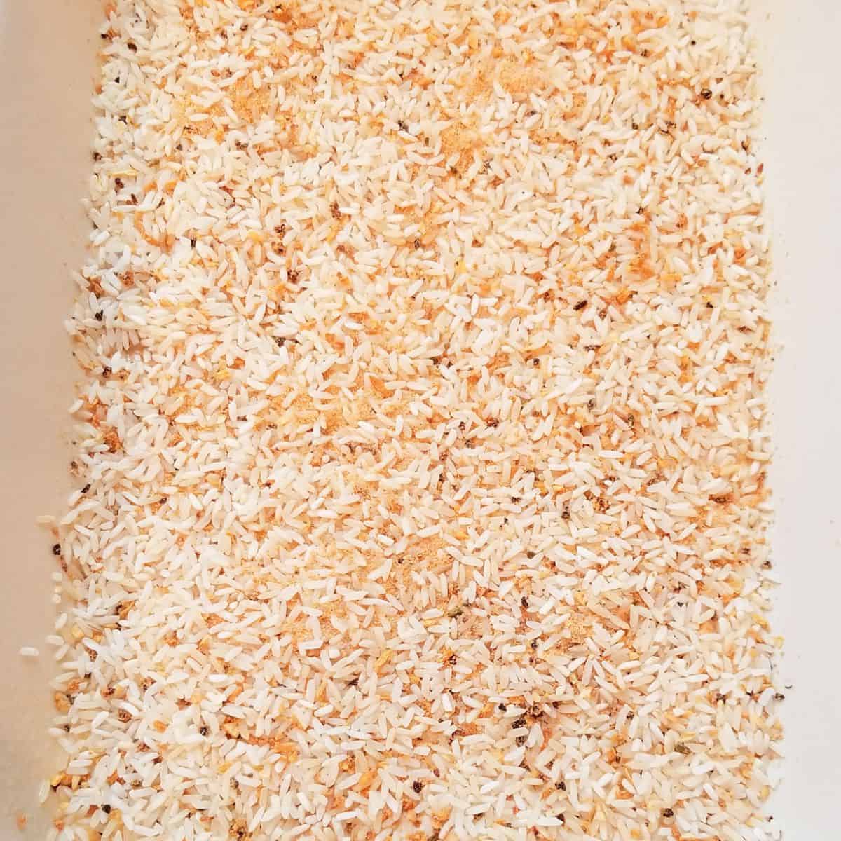 Yellow rice in the bottom of a casserole dish.