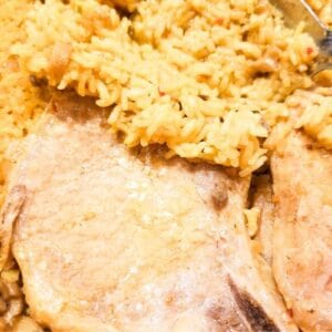 Pork chops and yellow rice in a baking dish.