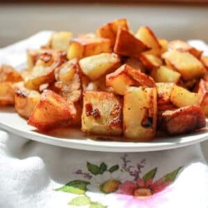 Finished dish of fried potatoes and onions in a white bowl.