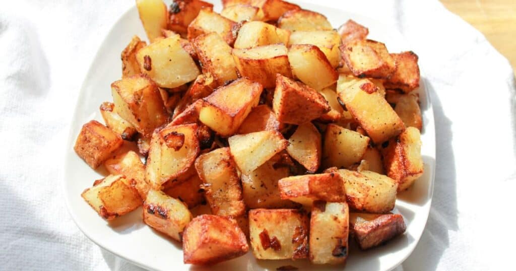 A finished recipe of potatoes and onions in a white bowl.