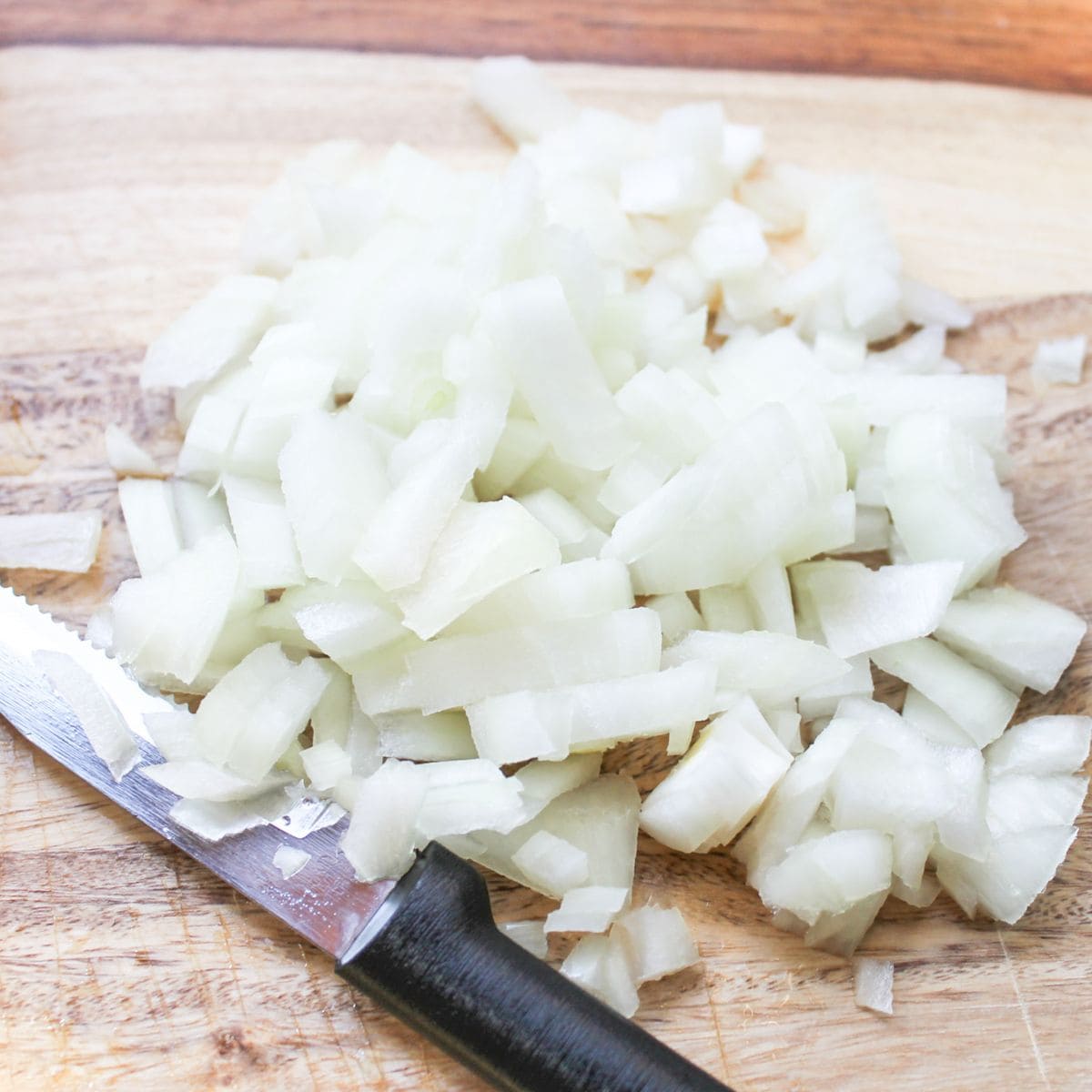 Diced onions on a cutting board with a knife.