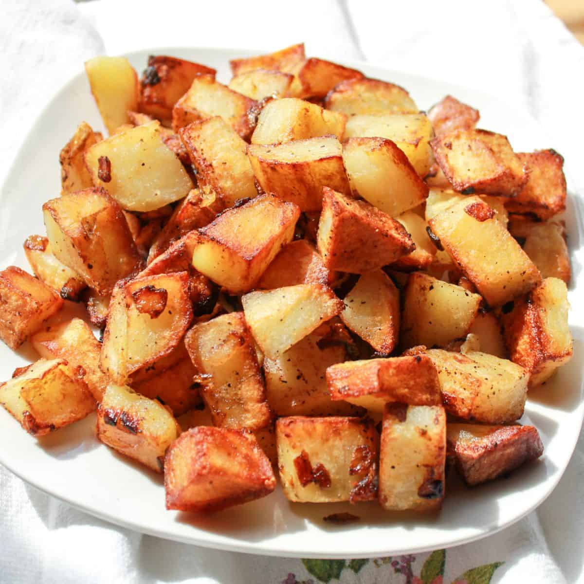 Fried potatoes and onions on a white plate.