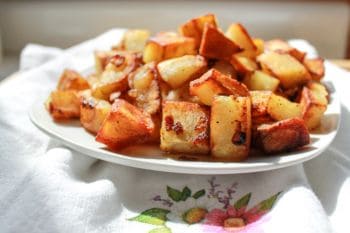 Fried potatoes and onions in a white bowl.