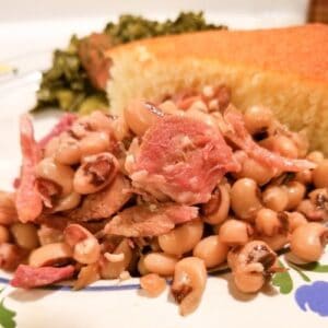 Slow cooker purple hull peas on a plate with cornbread and greens.