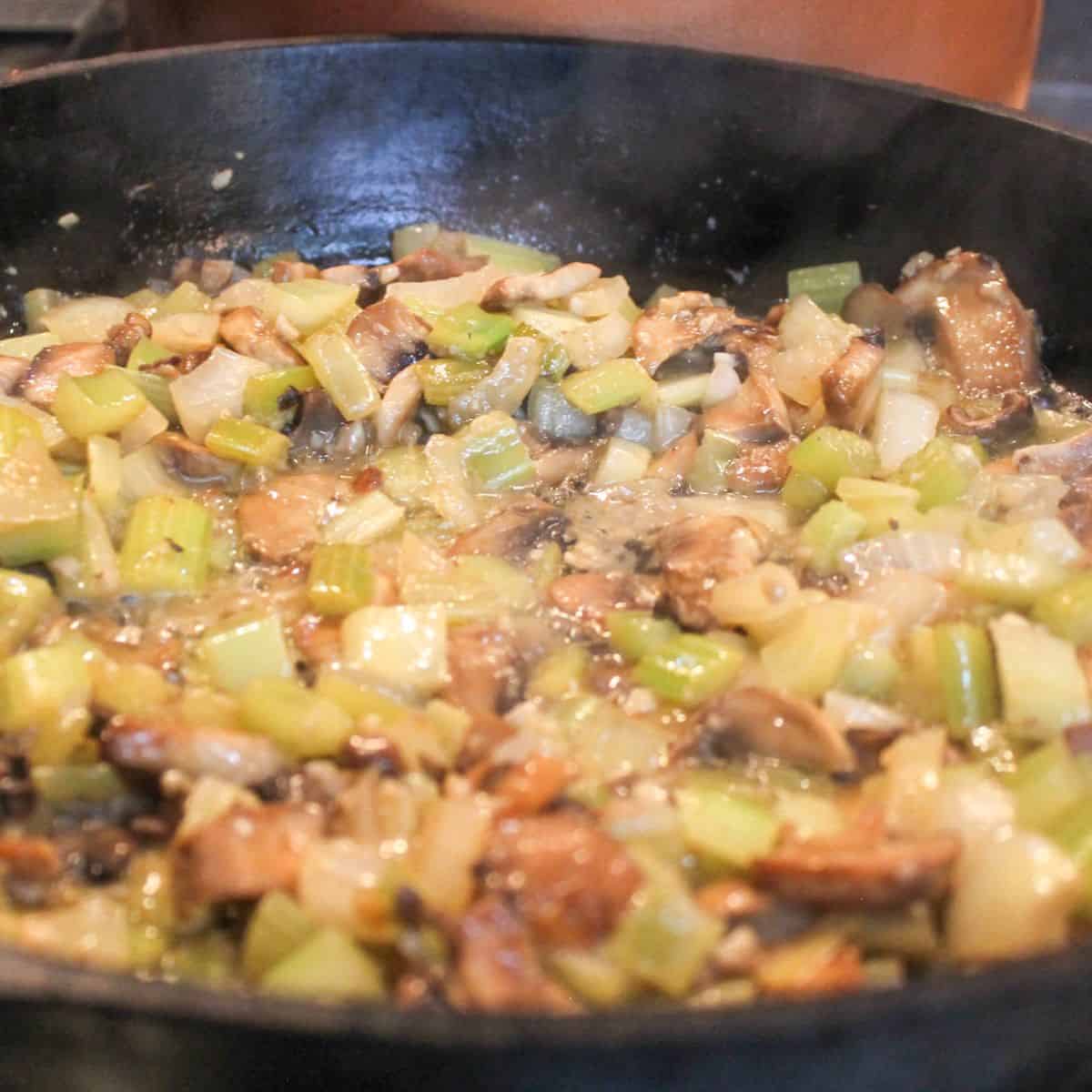 Vegetables cooking in a black skillet.