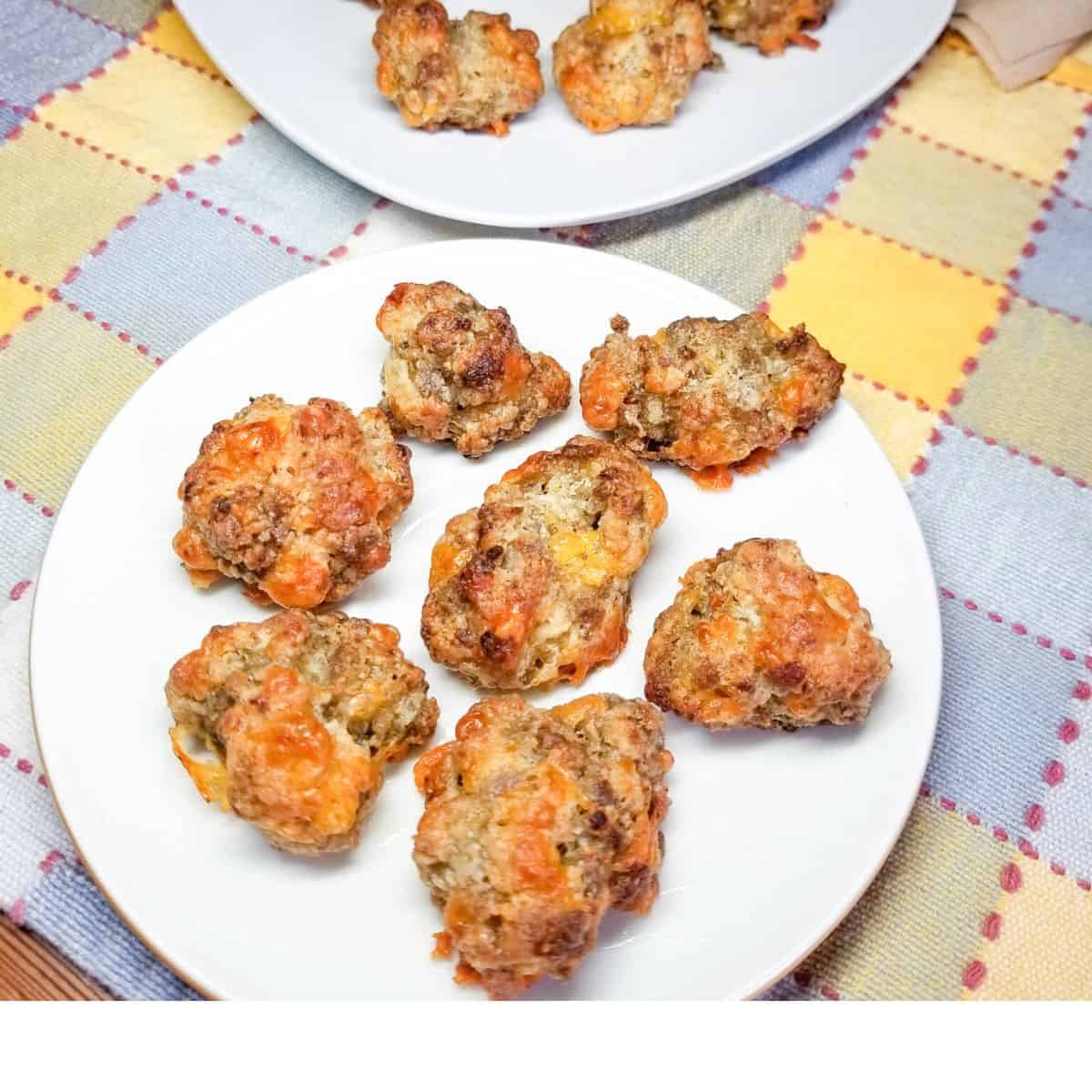 Cooked sausage balls on a white plate and platter.