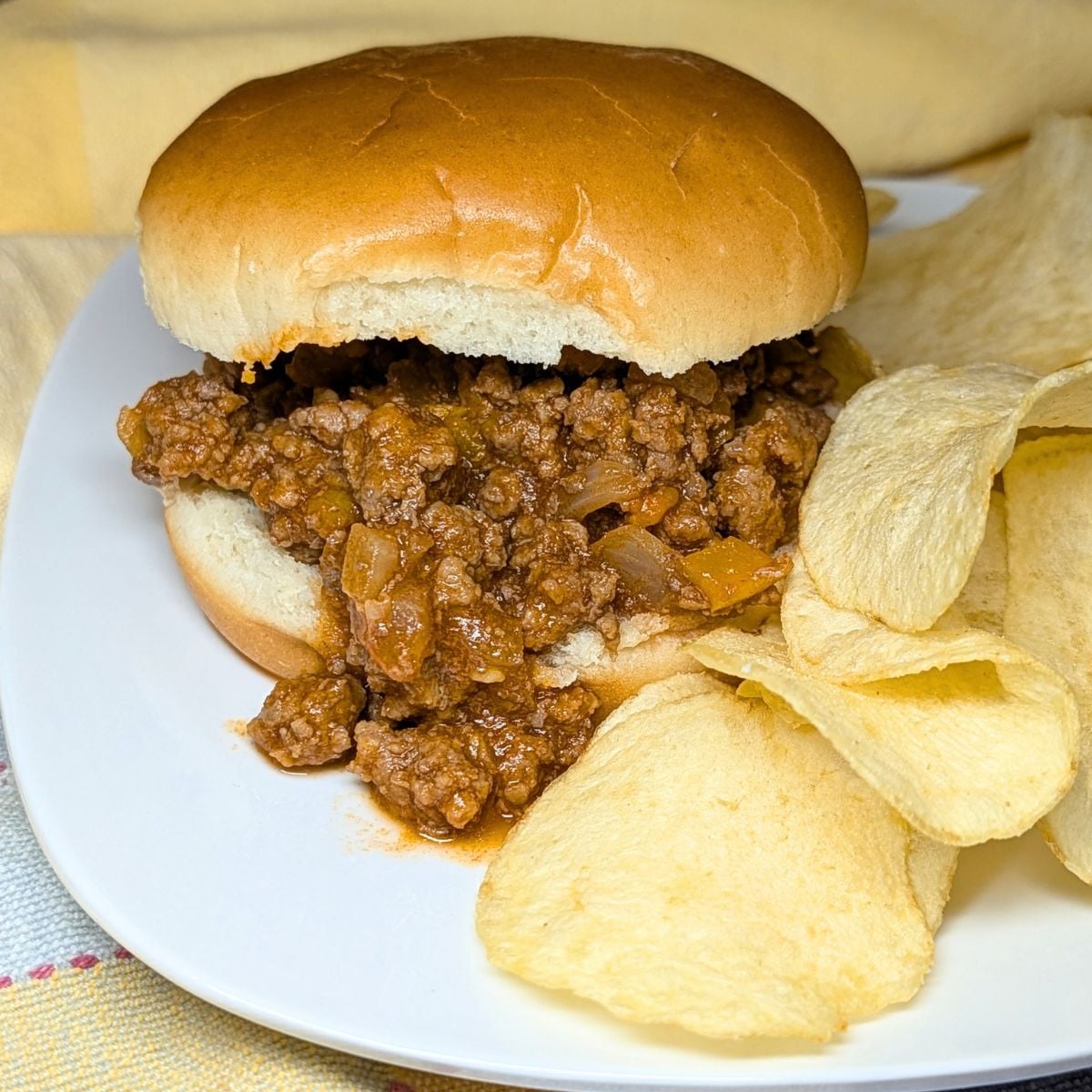 Sloppy Joe on a bun with chips on the side.