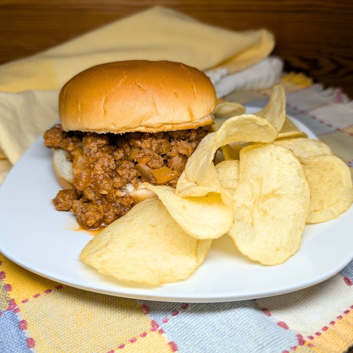 Homemade sloppy joe on a bun with chips on the side.