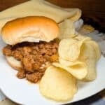 Sloppy joe on a bun with chips on the side.