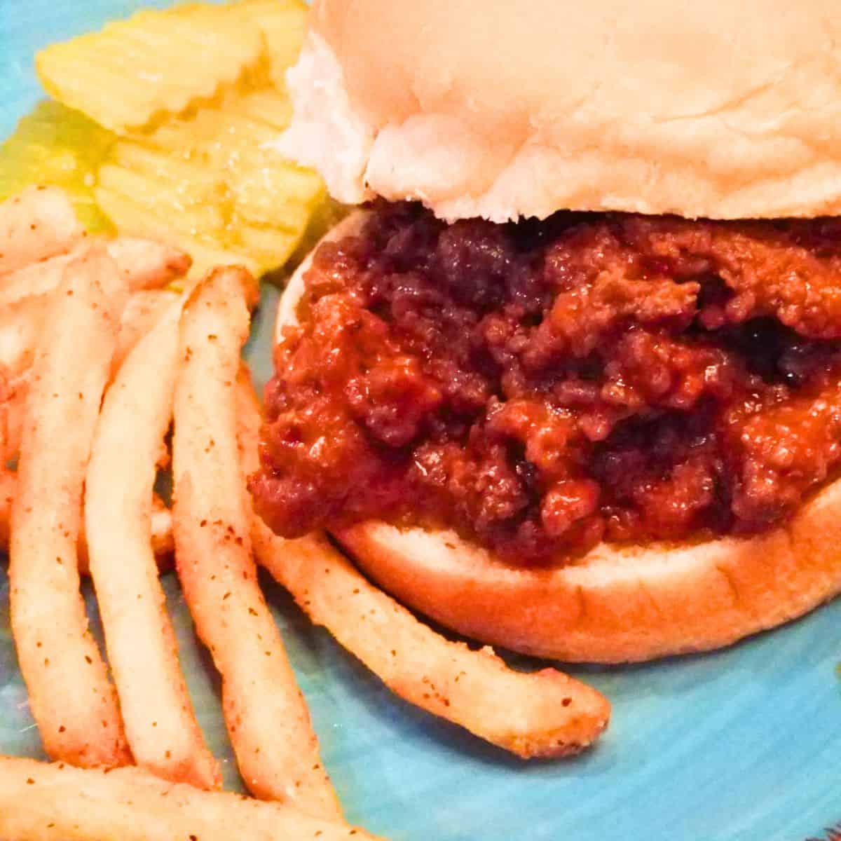 Sloppy joe sandwich served with fries and pickles for an easy weeknight dinner.