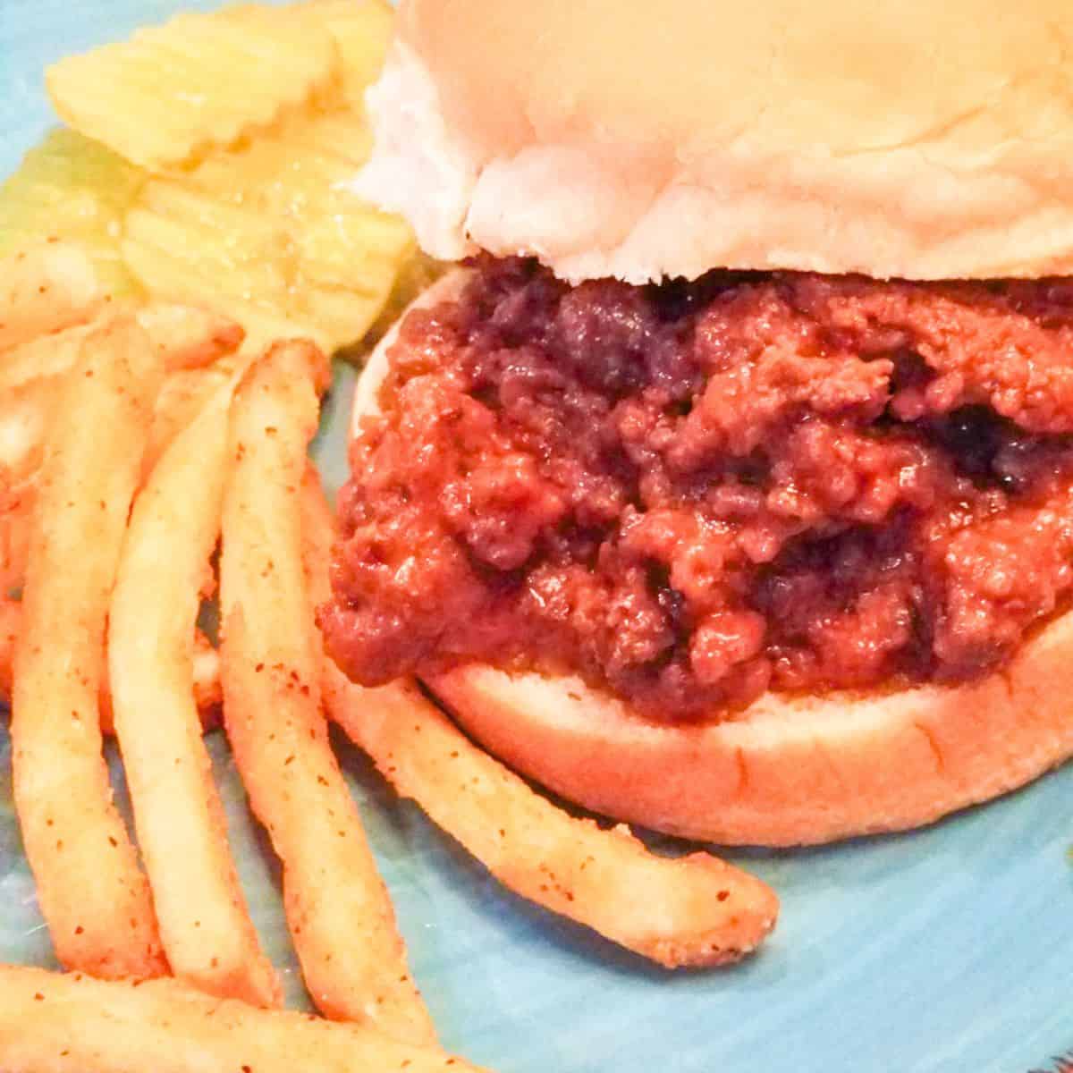 Ground beef sloppy joes on buns ready to serve for family dinner with fries and pickles.