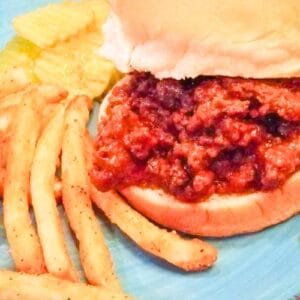 Easy sloppy joes on a bun with fries and pickles on the side.