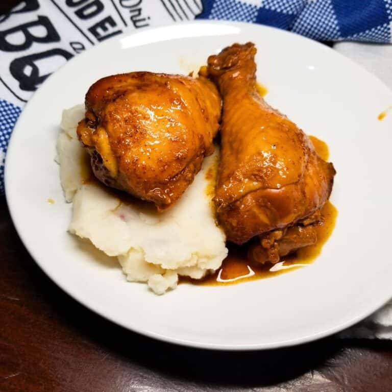BBQ chicken over mashed potatoes in a white serving bowl.