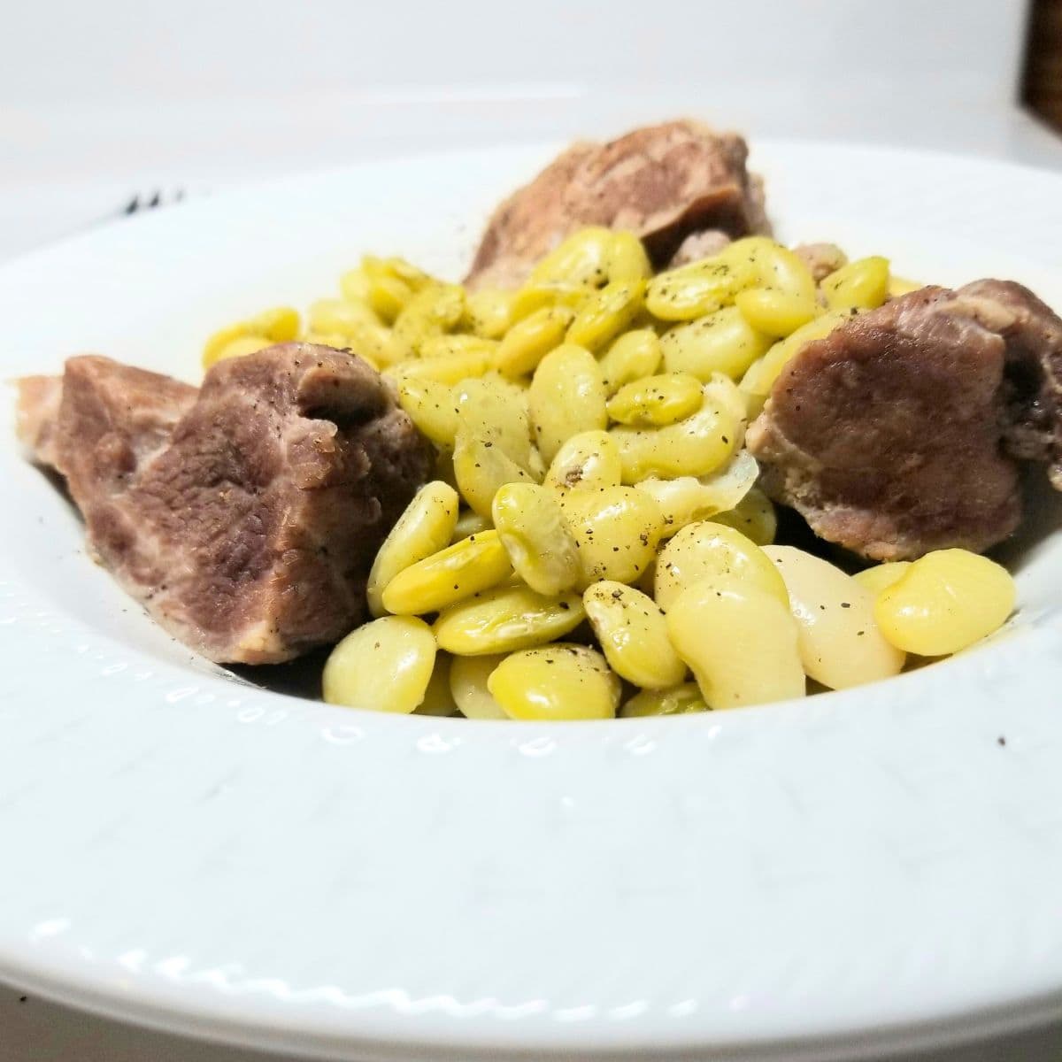 Bowl of Southern lima beans with neckbones simmered in rich broth, served in a white bowl.