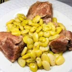 Close-up of slow-simmered Southern lima beans with meat in a white bowl.