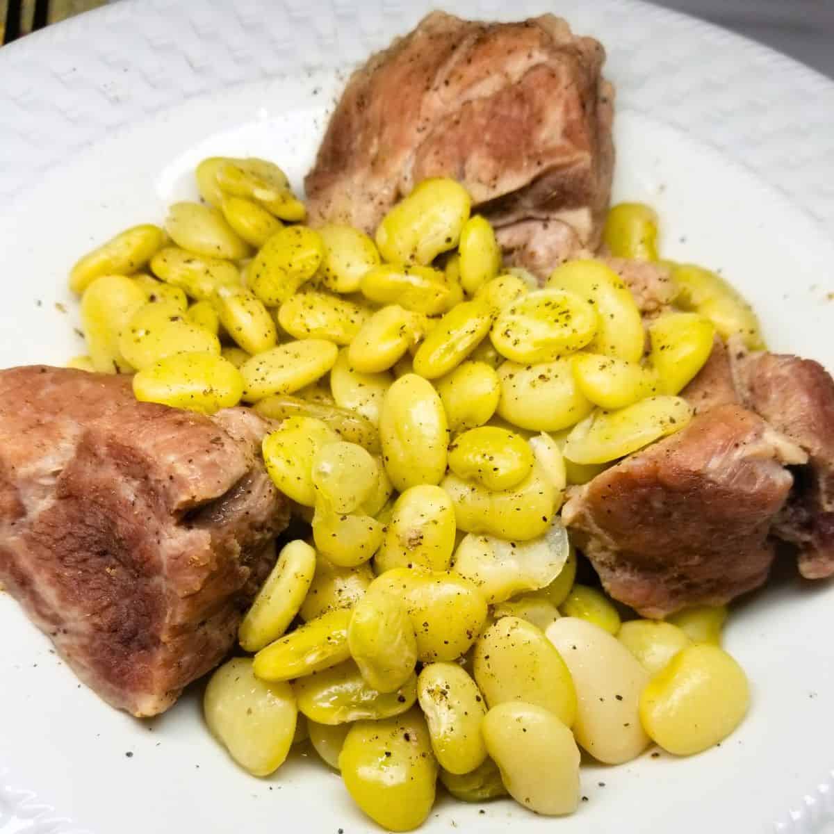 Bowl of Southern lima beans with neckbones simmered in rich broth, served with cornbread in a white bowl.