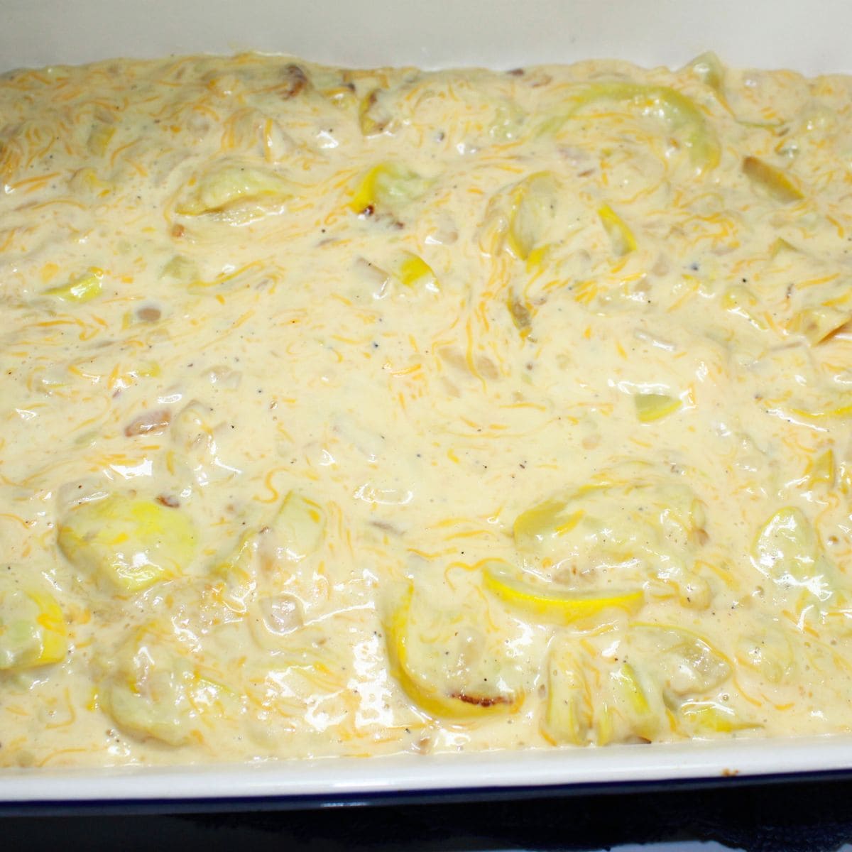 Squash casserole mixture combined in a casserole dish.