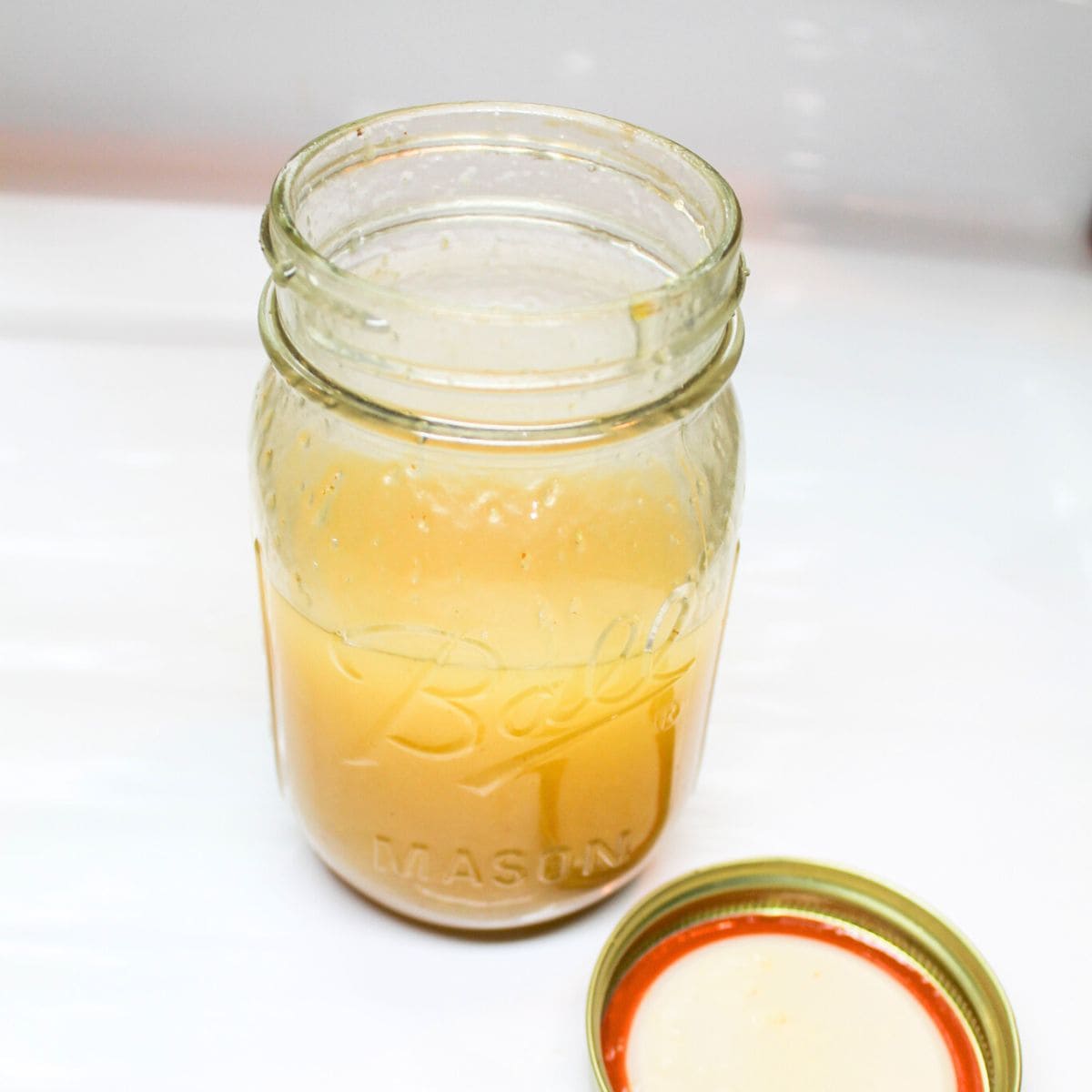 A Mason jar with dressing for the strawberry spinach salad.