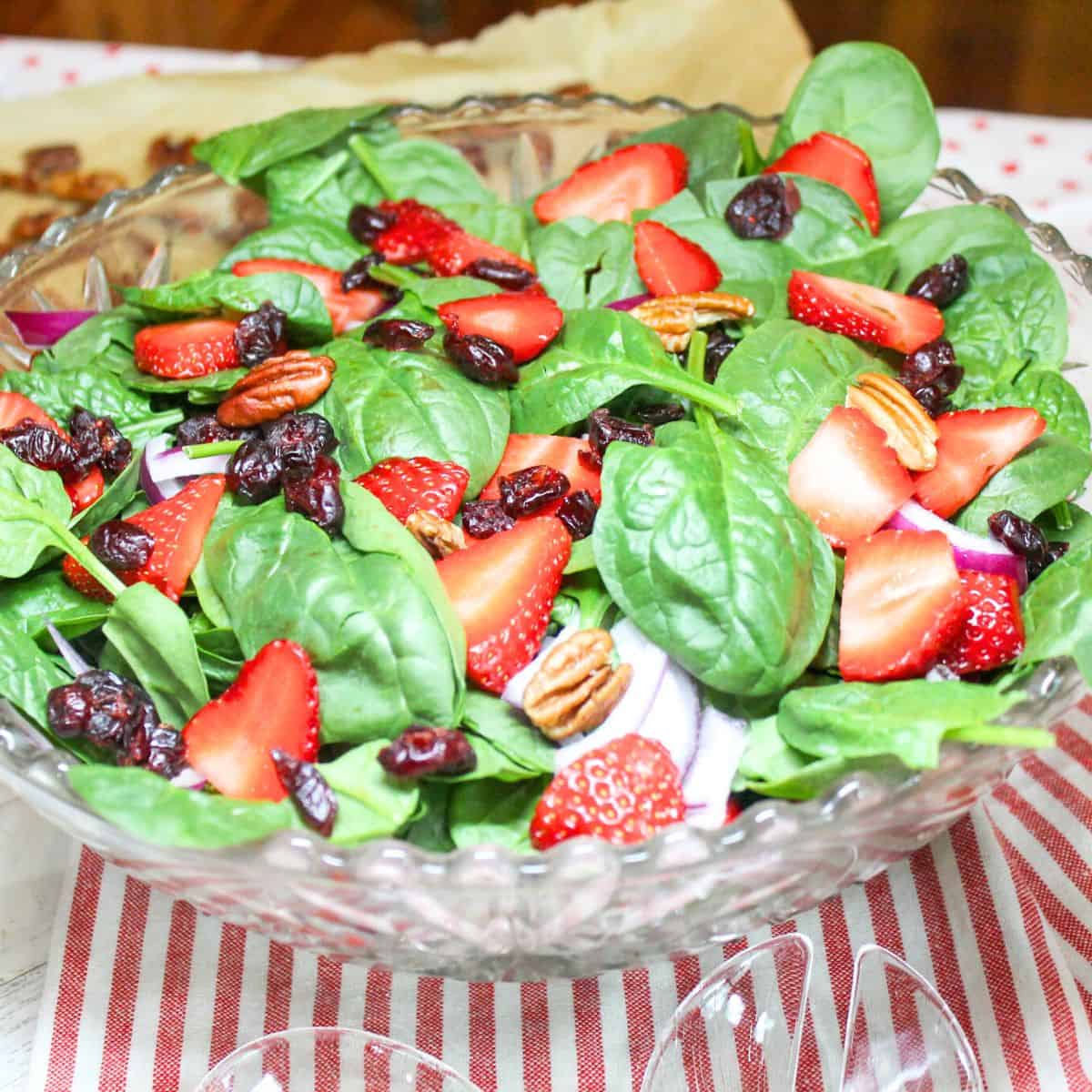 Summer salad made with baby spinach, sliced strawberries, dried cranberries, and toasted pecans.