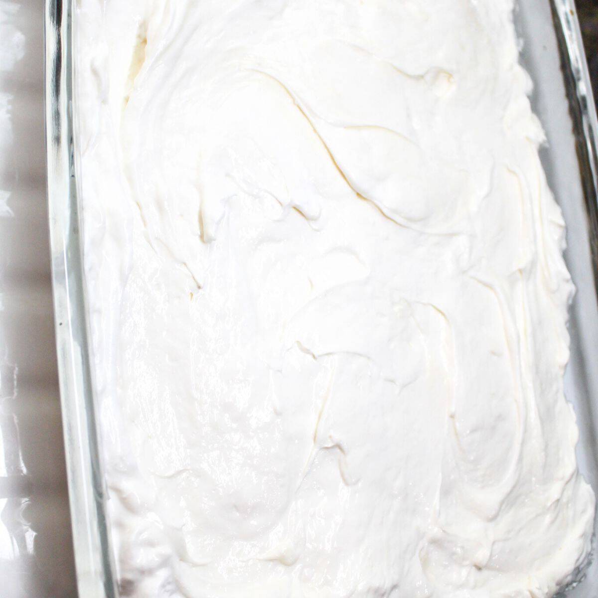 Cream cheese filling and graham cracker crust in a baking dish.
