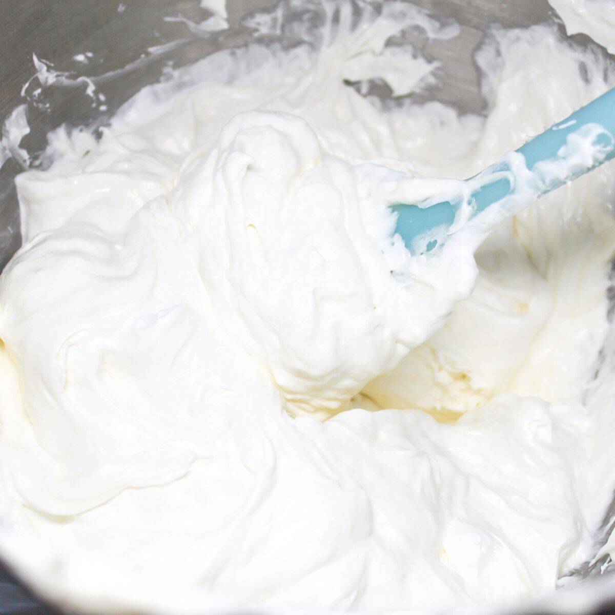 Cream cheese and ingredients being mixed together until smooth and creamy then adding cool whip.