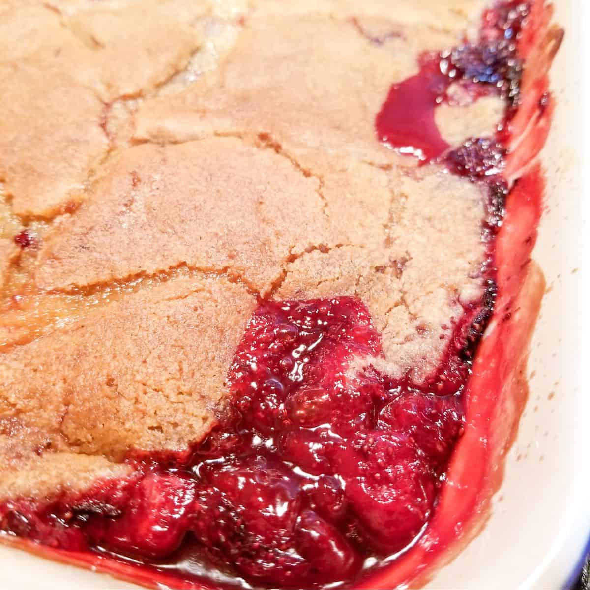 Baked strawberry cobbler in a blue baking dish.