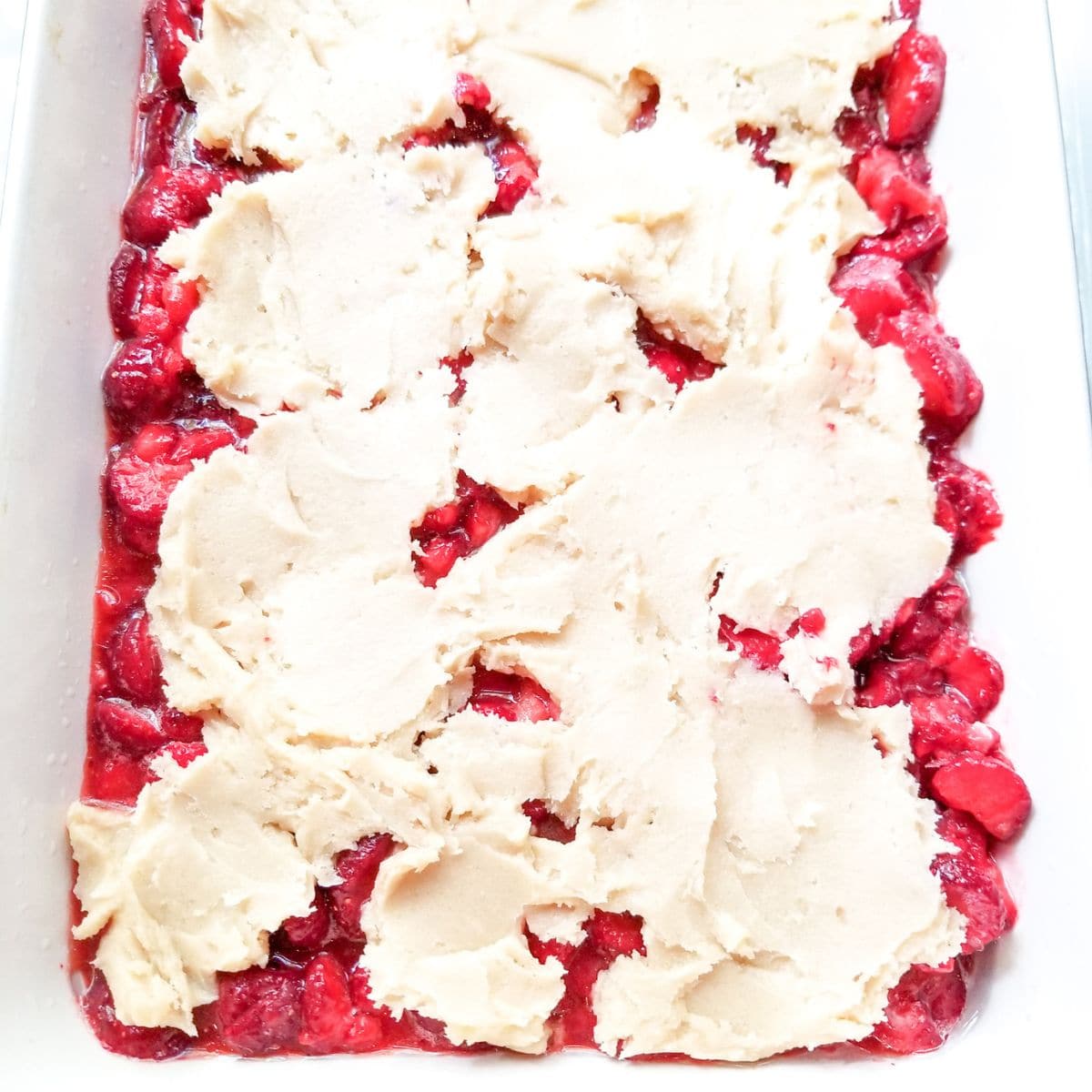 Sliced strawberries and topping in a baking dish.