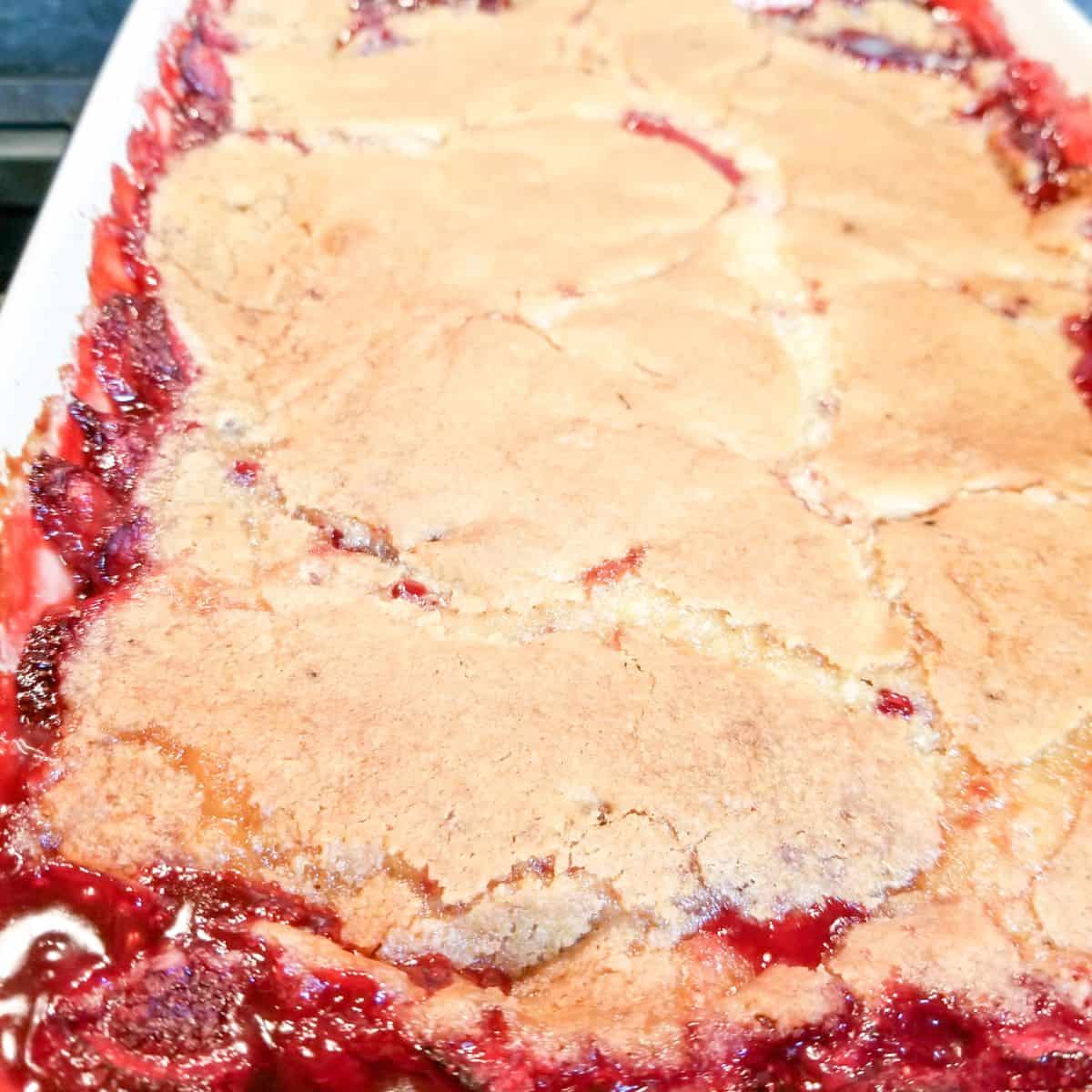 Baked strawberry cobbler in a blue baking dish.