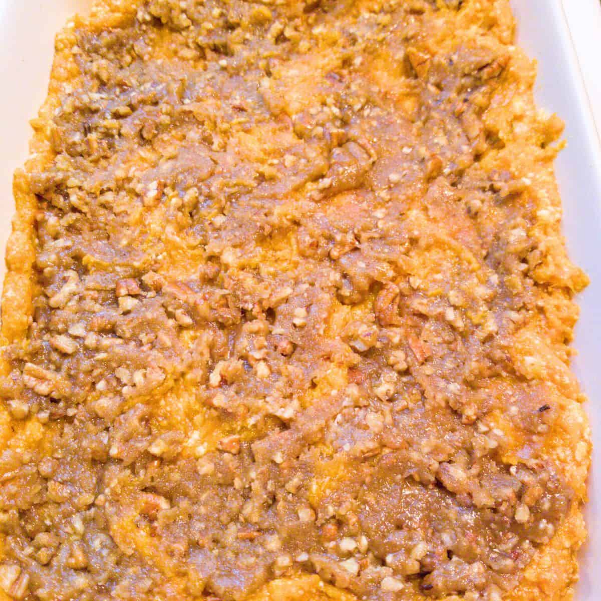 The topping spread across the sweet potato filling in a baking dish.