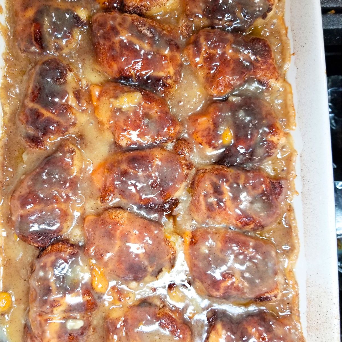 Golden brown sweet potato dumplings bubbling in cinnamon syrup after baking.