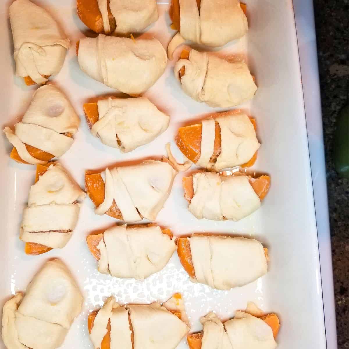 Sweet potato pieces wrapped in crescent dough and placed in baking dish.
