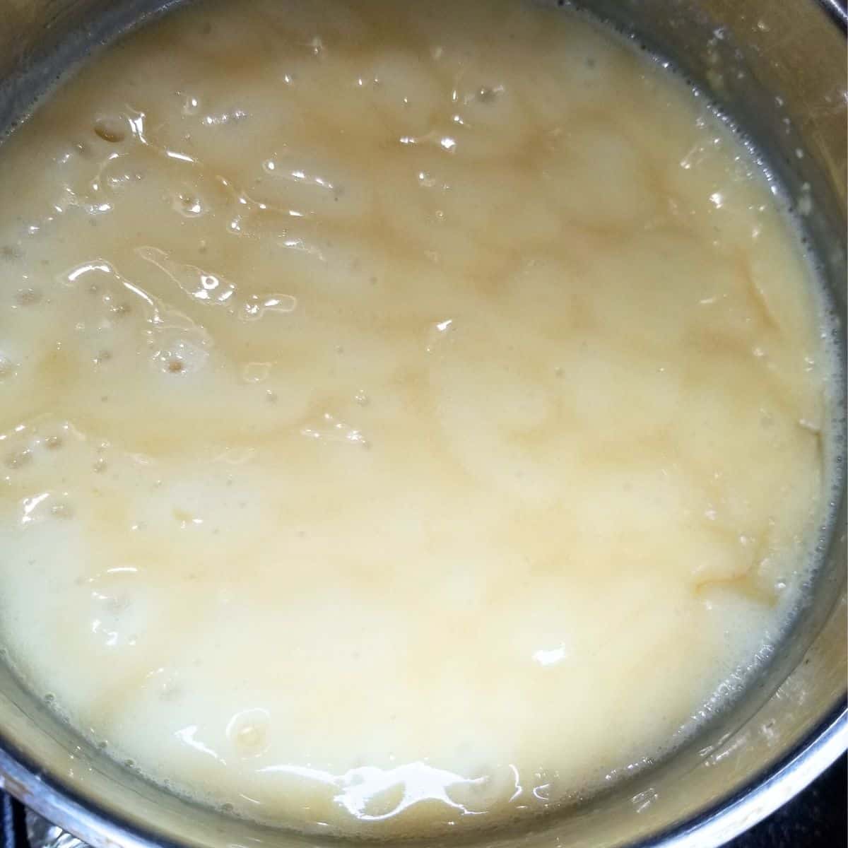 Evaporated milk, sugar, salt, butter, and cornstarch cooking in a saucepan for sauce.