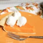 Sweet potato pie with whipped topping on a brown plate with a fork.