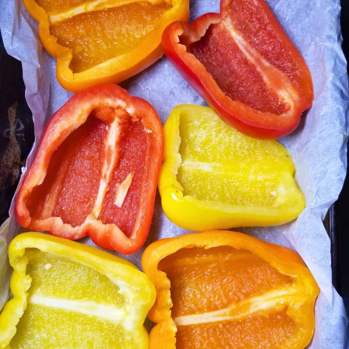 Red, yellow, and orange bell peppers cut in half.