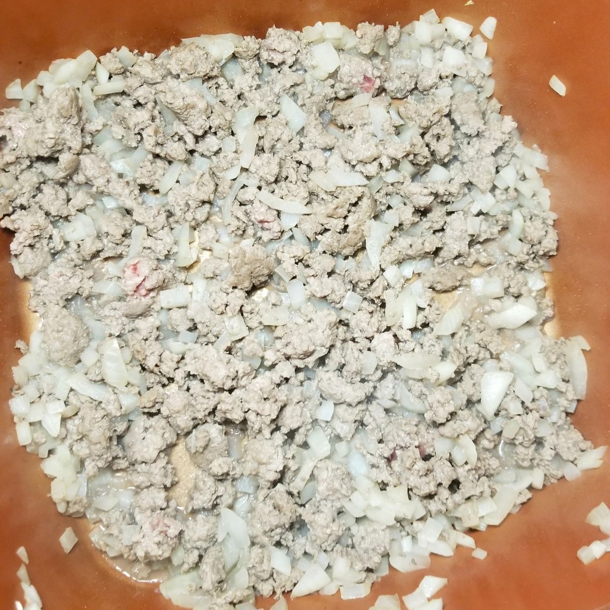 Cooked ground beef and onions in a skillet.
