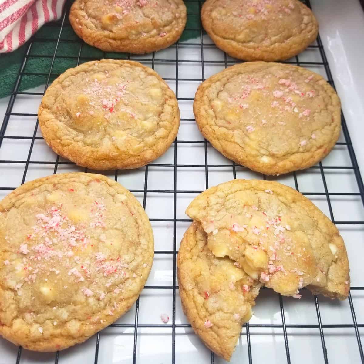 Baked cookies cooling on a wire rack with a stripped dish towel.