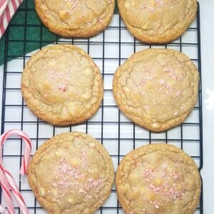 Peppermint cookies on a wire rack with candy canes and dish towels.