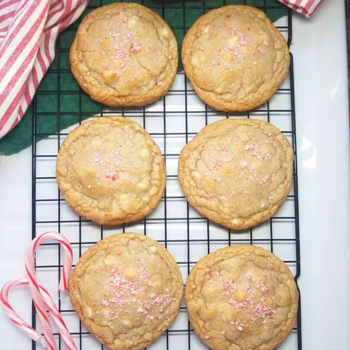 Baked cookies cooling on a wire rack with peppermint candy and a dish towel.