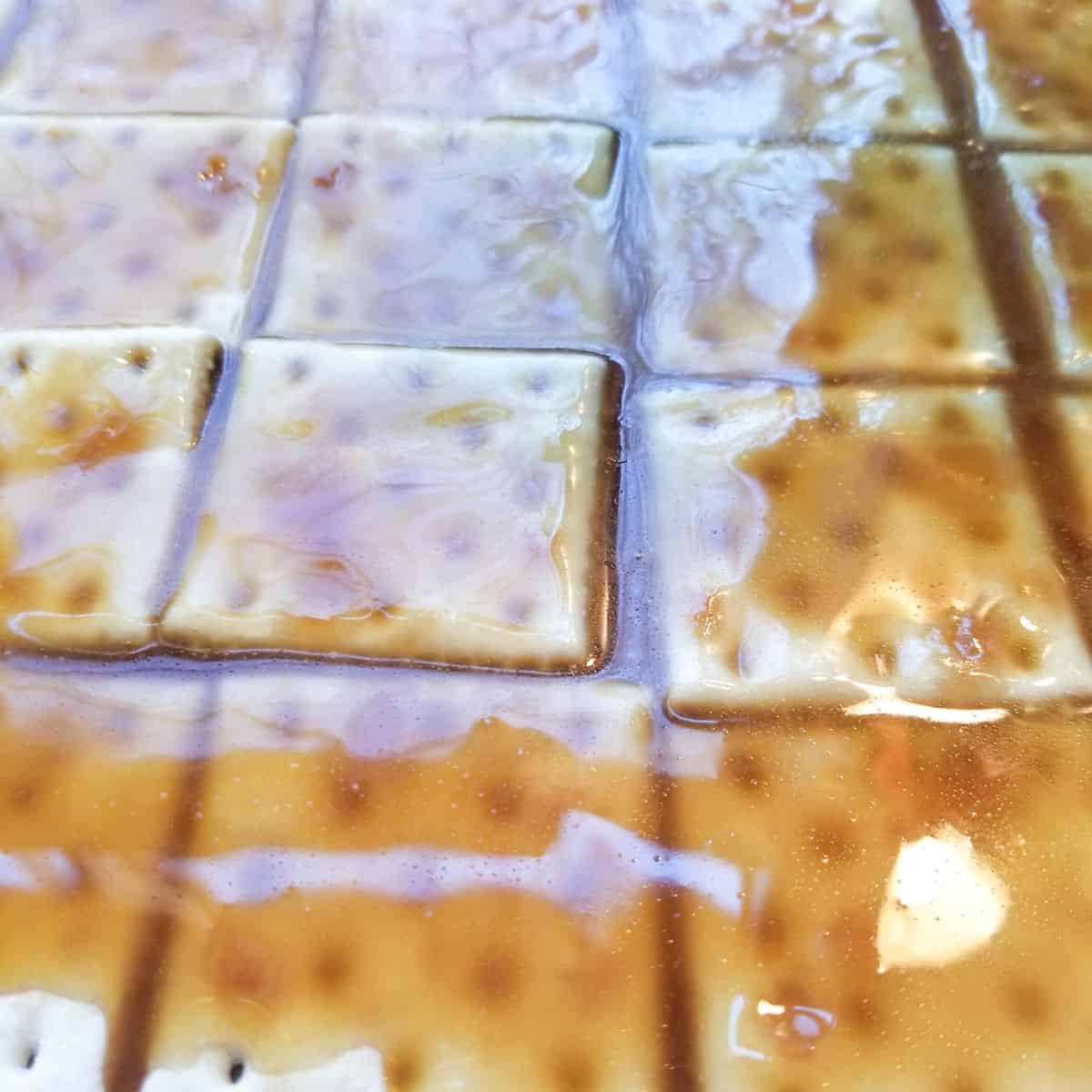 Baking toffee on saltine crackers on a baking sheet.