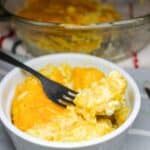 Yellow rice and corn casserole in a white bowl with a fork.