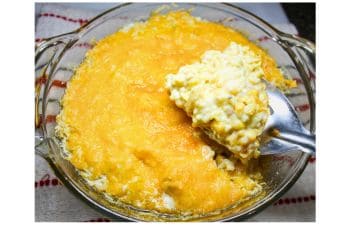 Yellow rice and corn casserole in a baking dish with a serving spoon.