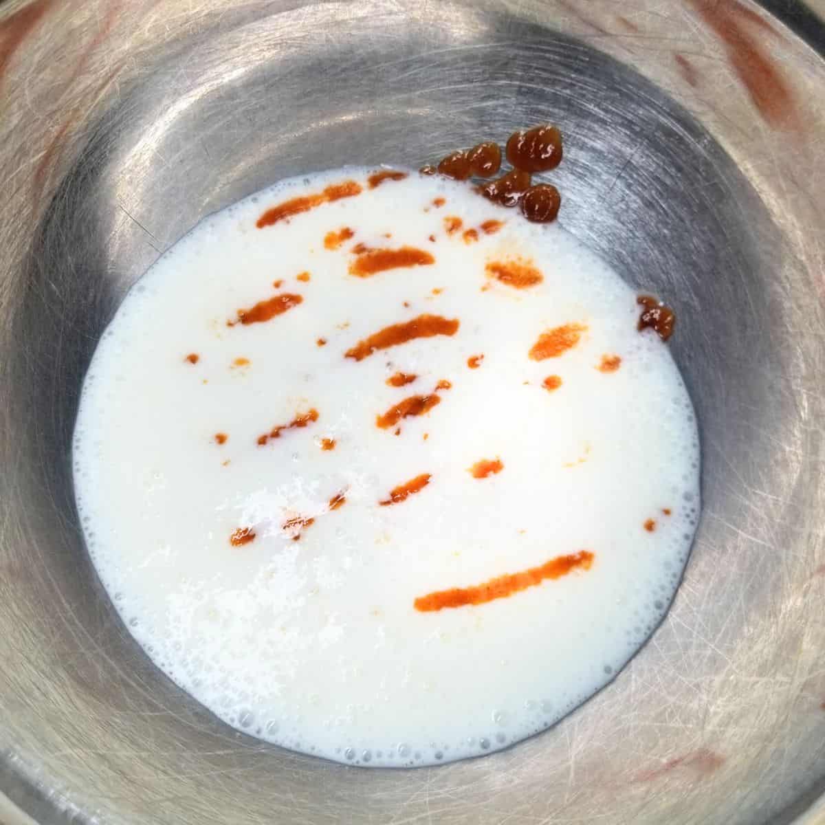 A bowl with buttermilk and hot sauce.