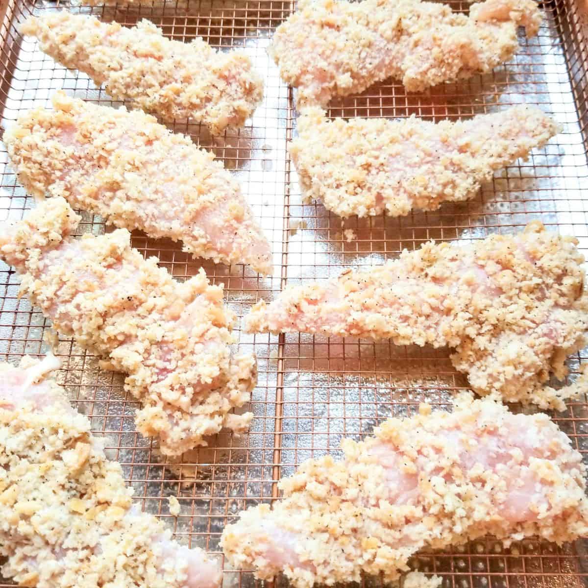 Breaded chicken on a wire rack ready for the oven.